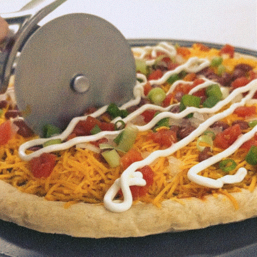 Pizza with shredded cheddar, green onions, tomatoes, beans and sour cream