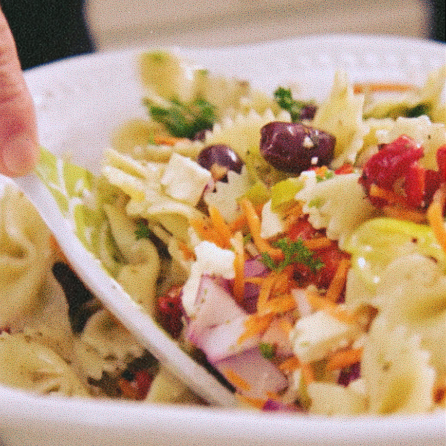 Greek Pasta Salad being mixed up