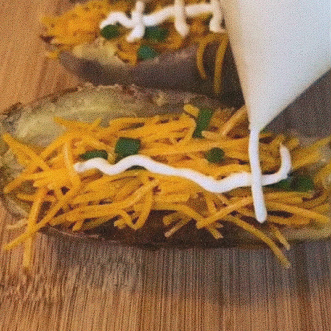 potato skins with cheddar and sour cream being applied