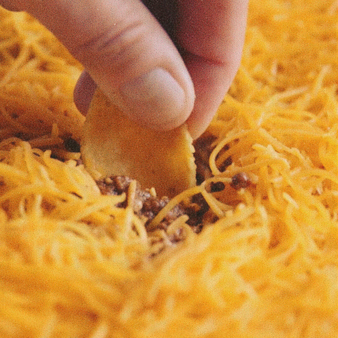 Hand dipping chip into skyline chili dip