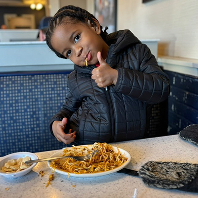 Child giving a thumbs up while eating skyline
