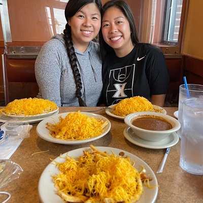 Two women posing with smiles at Skyline with a table full of food