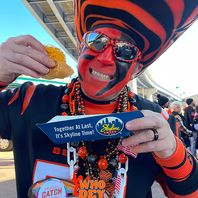 Cincinnati bengals fan with face paint and cincinnati bengals outfit eating a coney and smiling