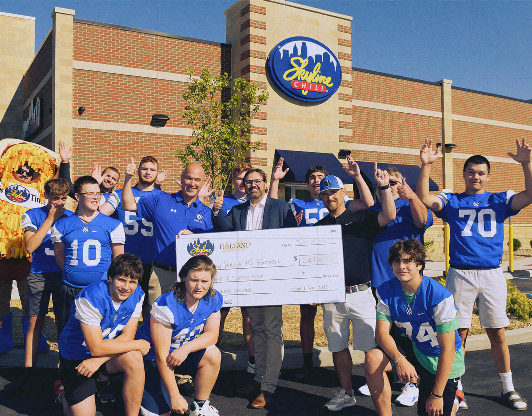 Teenage High School Football players standing in front of a Skyline restaurant with a donation check